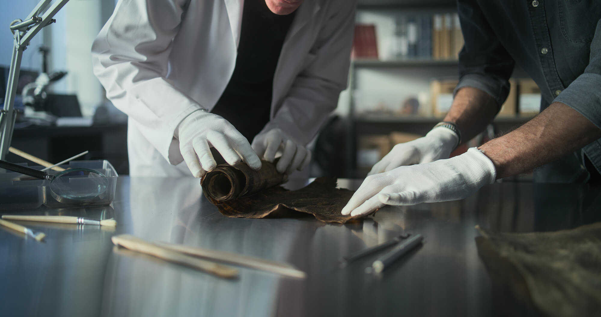 Unrolling a papyrus scroll to verify the authenticity of the artwork