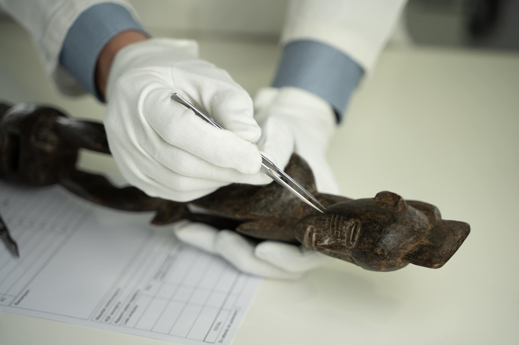 A scientist taking a sample from a wooden statue