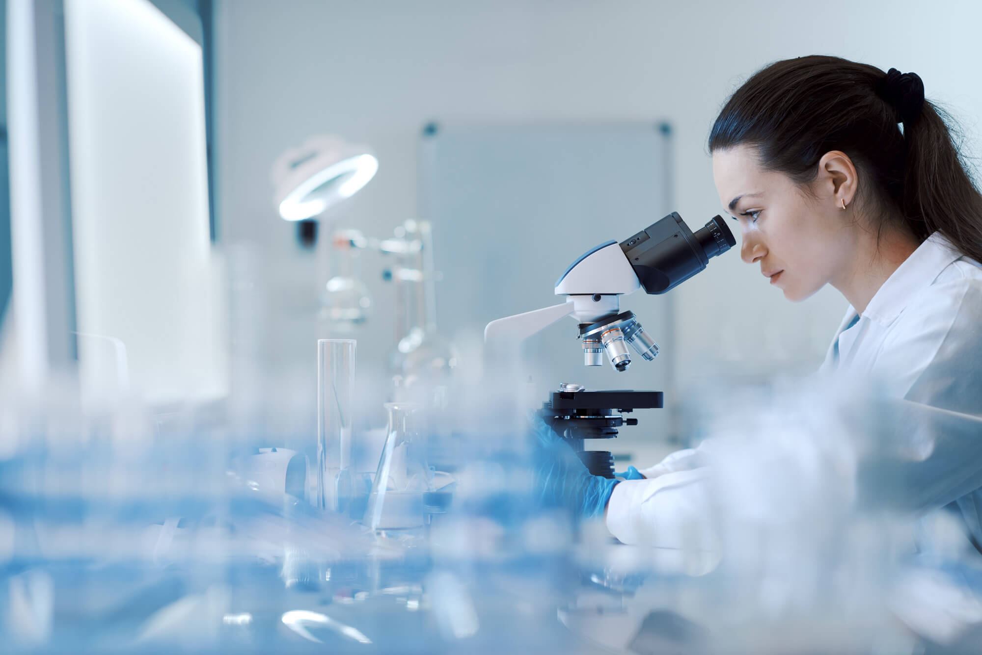 Scientist using a microscope in an accredited laboratory